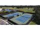 Aerial shot of the tennis courts surrounded by golf course, trees, and water at 1853 San Silvestro Dr, Venice, FL 34285