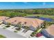 Stunning aerial view of attached villa homes with tile roofs, lush landscaping, a pond, and a golf course nearby at 1853 San Silvestro Dr, Venice, FL 34285
