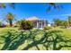 Well-manicured backyard with a screened-in patio, palm trees, and lush landscaping at 1853 San Silvestro Dr, Venice, FL 34285