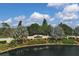 Beautiful community entrance with lush landscaping, mature palm trees, and a tranquil pond at 1853 San Silvestro Dr, Venice, FL 34285
