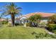 A sunny front exterior view of a well kept home with tropical landscaping and well manicured green lawn at 1853 San Silvestro Dr, Venice, FL 34285