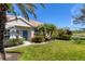 A sunny front exterior view with a cheerful turquoise front door and beautifully maintained landscaping and lawn at 1853 San Silvestro Dr, Venice, FL 34285