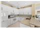 White kitchen with stainless appliances, tile backsplash and bar with seating at 1853 San Silvestro Dr, Venice, FL 34285