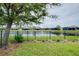 Picturesque backyard with a black metal fence, lush greenery, and a serene lake view at 20176 Tesoro Dr, Venice, FL 34293