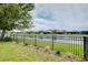 Beautiful backyard featuring a black metal fence, green grass, landscaping, and serene lake views at 20176 Tesoro Dr, Venice, FL 34293
