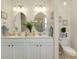 Bathroom featuring a double vanity, framed mirrors, ample counter space, and a decorative light fixture at 20176 Tesoro Dr, Venice, FL 34293