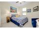 Cozy bedroom featuring a blue and white checkered bedspread, beach-themed wall art, and a comfortable blue chair at 20176 Tesoro Dr, Venice, FL 34293