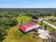 Expansive property featuring lush green space, mature trees, and a red-roofed house with an outdoor patio at 2211 Englewood Rd, Englewood, FL 34223