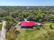 Aerial view of a home with a red roof and blue siding on a spacious lot with mature trees at 2211 Englewood Rd, Englewood, FL 34223