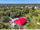 Aerial view of a home with a red roof and blue siding set amongst green landscape with some trees at 2211 Englewood Rd, Englewood, FL 34223