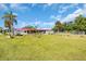 Spacious backyard featuring a well-maintained lawn, palm trees, and a charming single-story home with a red roof at 2211 Englewood Rd, Englewood, FL 34223