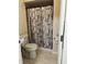 Compact bathroom featuring a toilet, sink, and walk-in shower, complete with a shower curtain and neutral tile at 2211 Englewood Rd, Englewood, FL 34223