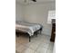 Minimalist bedroom featuring neutral walls, tiled floors, and a cozy bed with striped bedding and a ceiling fan at 2211 Englewood Rd, Englewood, FL 34223