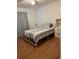 A bedroom featuring a twin bed with striped bedding, wood-look flooring and patterned curtains at 2211 Englewood Rd, Englewood, FL 34223