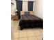 A cozy bedroom featuring a twin bed with a plaid comforter, neutral wall color, and tile flooring at 2211 Englewood Rd, Englewood, FL 34223