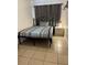 A bedroom featuring a twin bed with striped bedding, a metal frame, tile flooring, and a dark curtain at 2211 Englewood Rd, Englewood, FL 34223