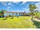 Charming home exterior with green lawn, lush landscaping, and inviting walkway with red roof at 2211 Englewood Rd, Englewood, FL 34223
