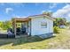 Charming exterior showcasing a cozy covered porch, a well-maintained lawn, and classic design at 2211 Englewood Rd, Englewood, FL 34223