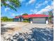 Exterior of a home with a red roof, blue siding, a two-car garage, and a concrete driveway at 2211 Englewood Rd, Englewood, FL 34223