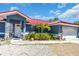 Charming home featuring a red roof, blue siding, a well-manicured front garden, and an attached garage at 2211 Englewood Rd, Englewood, FL 34223