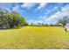 A large field with green grass surrounds a home and is framed by mature trees and blue sky at 2211 Englewood Rd, Englewood, FL 34223