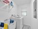 Clean laundry room with a washer, dryer, utility sink, and shelving for storage at 2211 Englewood Rd, Englewood, FL 34223