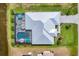 Aerial view of home featuring screen enclosed pool and patio, lush lawn, and modern roof design at 226 W Pine Valley Ln, Rotonda West, FL 33947