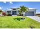 Beautiful single-story home featuring lush landscaping, a gray garage door, and a pristine white exterior at 226 W Pine Valley Ln, Rotonda West, FL 33947