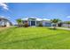 Expansive green lawn complements this single-story home with meticulous landscaping, palms, and gray brick driveway at 226 W Pine Valley Ln, Rotonda West, FL 33947