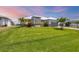 Expansive green lawn complements this single-story home with meticulous landscaping, palms, and gray brick driveway at 226 W Pine Valley Ln, Rotonda West, FL 33947