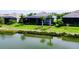 Backyard with lush green grass and tropical trees overlooking a serene pond at 265 Bocelli Dr, Nokomis, FL 34275