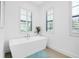 Bright bathroom with a modern freestanding tub, large windows with shutters, and neutral tile floors at 265 Bocelli Dr, Nokomis, FL 34275