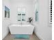 Bright bathroom with a modern freestanding tub, large windows with shutters, and neutral tile floors at 265 Bocelli Dr, Nokomis, FL 34275