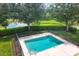 Aerial view of the fenced community pool next to lake with lush trees and plants at 3226 58Th E Ter, Bradenton, FL 34203