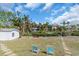 Spacious backyard featuring a shed, lounge chairs, kayaks, and lush landscaping by the waterfront at 328 Channel Ln, Nokomis, FL 34275