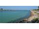 Scenic waterfront view showcasing clear turquoise water, rocky shoreline, and lush greenery at 328 Channel Ln, Nokomis, FL 34275