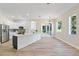 Bright, open kitchen features white cabinets, stainless appliances, an island, and wood-look tile flooring at 3470 Elias Cir, North Port, FL 34288