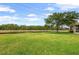 Expansive backyard with lush green grass, a serene pond, and mature trees at 371 Capulet Dr, Venice, FL 34292