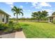 Expansive backyard with lush green grass, mature trees, and a view of a pond in the distance at 371 Capulet Dr, Venice, FL 34292