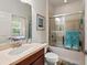 Comfortable bathroom featuring a vanity with dark wood cabinets, a shower with glass doors, and a window view at 371 Capulet Dr, Venice, FL 34292