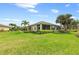 Green home exterior with well-maintained landscaping, screened lanai, and palm trees at 371 Capulet Dr, Venice, FL 34292