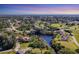 An aerial view of a residential area highlighting a home near a peaceful pond and green spaces at 440 Monza Ave, North Port, FL 34287