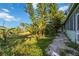 A lush backyard featuring mature trees and a tiled walkway for enjoying the tropical setting at 440 Monza Ave, North Port, FL 34287