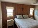 Cozy bedroom featuring wood paneling, a floral comforter, and dual windows at 530 Via Veneto, Venice, FL 34285