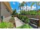 Side yard with a stone path, manicured flowerbeds, and a grill, perfect for outdoor cooking and relaxation at 740 Tanager Rd, Venice, FL 34293