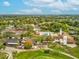 Expansive aerial view showcasing tennis courts and a clubhouse surrounded by verdant landscape and clear blue skies at 7515 Greystone Dr, Hudson, FL 34667