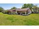 Rear view of a home featuring a well-kept lawn and cozy backyard patio with a grill at 7515 Greystone Dr, Hudson, FL 34667