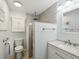 Stylish bathroom with a modern vanity, toilet, storage cabinet, and a glass-enclosed shower with gray tiling at 7515 Greystone Dr, Hudson, FL 34667