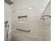 Close-up of a shower featuring modern gray tile, a built-in niche, and updated fixtures with safety bar at 7515 Greystone Dr, Hudson, FL 34667