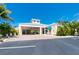 Exterior of a community building with a covered entrance, palm trees, and ample parking at 8403 Placida Rd # 205, Placida, FL 33946